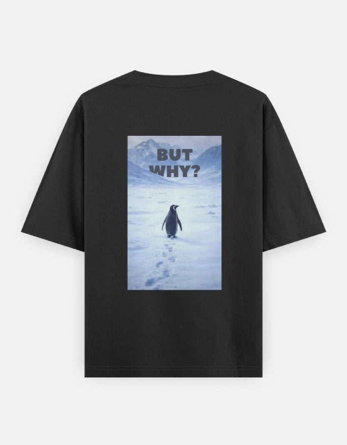 Back view of a black t-shirt featuring a rectangular graphic of a lone penguin walking across a snowy Antarctic landscape toward mountains with the text "BUT WHY?" in bold grey letters.
