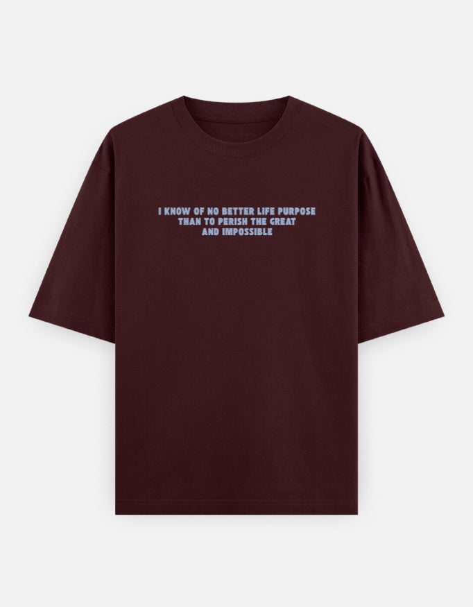 Front view of a maroon oversized t-shirt featuring the quote "I know of no better life purpose than to perish the great and impossible" printed in grey block letters across the chest.